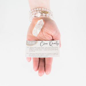 hand holding a clear quartz crystal and the why and how instruction card included with purchase